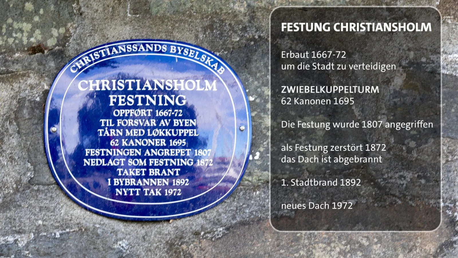 Zwei Informationstafeln zur Festung Christiansholm auf einer Steinmauer.